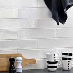 black and white coffee mugs sitting on top of a counter next to a towel rack