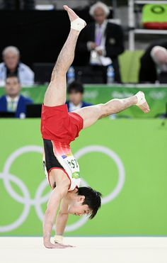 a man doing a handstand in front of an audience at the olympic games