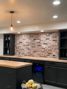 a bowl of fruit sitting on top of a kitchen counter next to a brick wall