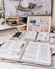 a laptop computer sitting on top of a desk next to an open book and notebook