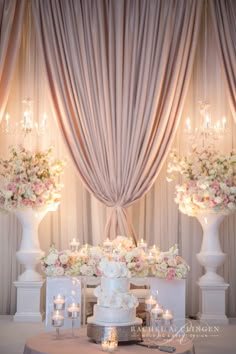 a wedding cake sitting on top of a table next to tall vases filled with flowers