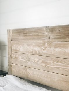 a bed with white sheets and wooden headboard