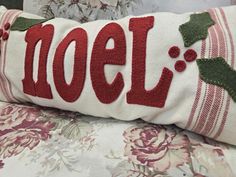 a close up of a pillow with the word noel embroidered on it and holly leaves