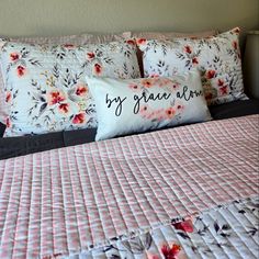 a bed with pink and white flowers on the comforter, pillows and pillow cases