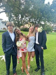 four people posing for a photo in the grass