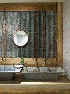 a bath tub sitting under a mirror next to a metal wall mounted faucet