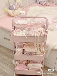 a pink cart filled with lots of baby items in a room next to a bed