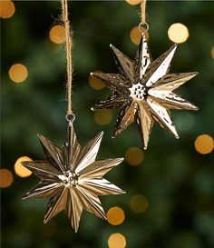 two gold stars hanging from strings on a christmas tree