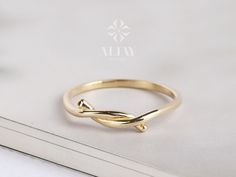 a gold ring with a twisted design on the front and side, sitting on top of a white book