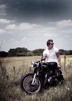 a man sitting on top of a motorcycle in a field