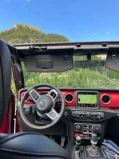 the interior of a jeep with mountains in the background and grass on the ground behind it