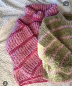 two knitted sweaters laying next to each other on top of a white blanket