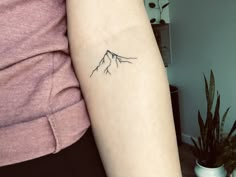 a woman's arm with a small mountain tattoo on the left side of her arm