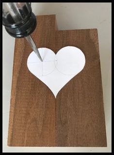 a piece of wood with a heart cut out on it and a drill in the middle