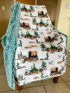 a blanket on top of a wooden chair covered in a cactus print with an image of a horse pulling a wagon