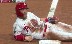 a baseball player laying on the ground next to a bat