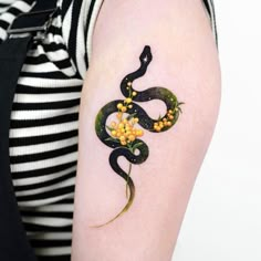 a woman's arm with a snake tattoo on it and flowers in the middle