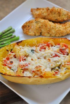 an eggplant stuffed with cheese and vegetables on a plate next to asparagus