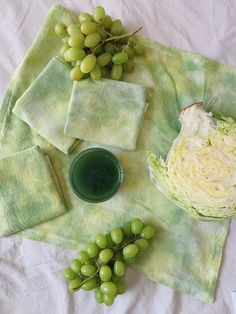 grapes, cabbage and green juice are on a table cloth with napkins next to them