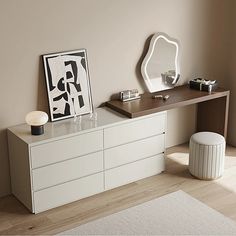 a white dresser sitting next to a mirror on top of a wooden table