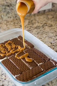 someone pouring peanut butter on top of some crackers in a baking dish with pretzels