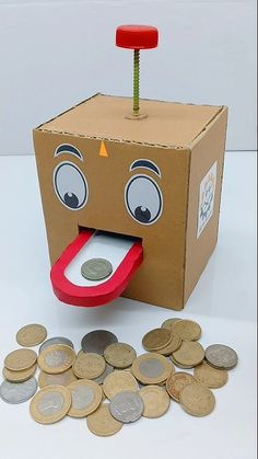 a cardboard box with a face and tongue sticking out from it next to some coins