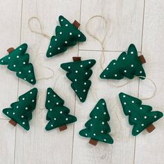 green felt christmas trees with white polka dots on them, tied to twine strings