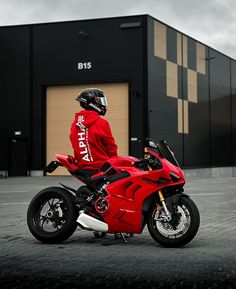 a person in a red jacket is sitting on a red motorcycle