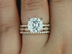 a woman's hand with a diamond ring on top of her wedding band and an engagement