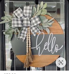 a wooden sign that says hello hanging on a door with a ribbon and tassel