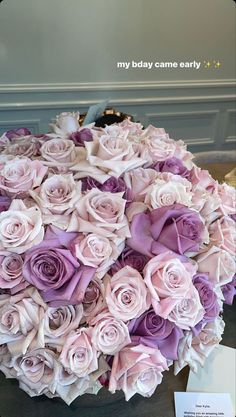 a large bouquet of pink and purple roses on display in a room with a name card