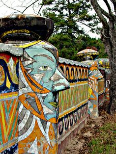 a colorfully painted fence with trees in the background