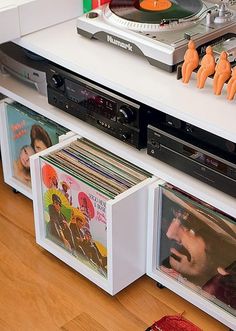 a record player sitting on top of a white shelf filled with cds and vinyl records