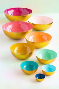 colorful bowls are lined up on a white surface with one empty bowl in the middle