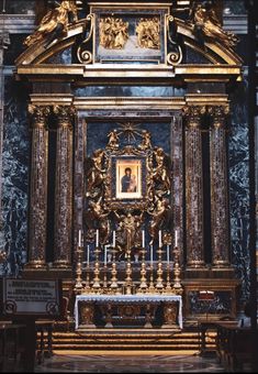 an ornate alter in a church with gold and black paint on the wall behind it