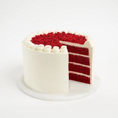 a red velvet cake with white frosting on a plate next to a slice cut out