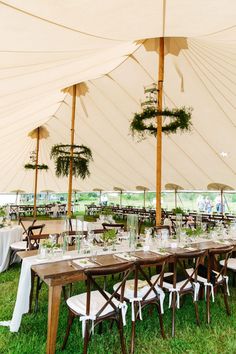 an outdoor tent with tables and chairs set up under umbrellas for a wedding reception