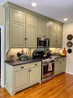 a kitchen with green cabinets and stainless steel stove top oven in the center of the room