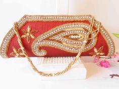 "A red clutch bag with gold bead trim. The statement handbag has a background of red taffeta, this is a brownish red. The front flap has a stunning design of gold and copper beading with rhinestones. The bag interior is red with one zipper pocket and a snap closure. The red beaded clutch also includes a beaded strap to wear on shoulder. This is a dazzling special occasion bag. It is large enough to hold an iPhone. MATERIAL: Beading, taffeta CONDITION: Good SIZE: 11\" wide and45: high COLOR: Brow Red Shoulder Bag For Festive Gift, Festive Red Shoulder Bag As Gift, Festive Red Shoulder Bag For Gifts, Handwork Red Shoulder Bag As Gift, Traditional Red Party Bag, Festive Red Shoulder Bag With Handwork, Red Rectangular Clutch With Handwork, Rectangular Red Clutch With Handwork, Red Rectangular Bags With Zari Work