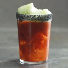 a close up of a drink on a table with food in the cup and garnish