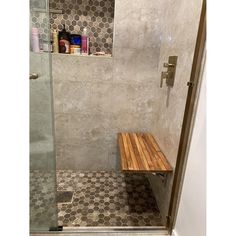 a walk in shower sitting next to a wooden bench on top of a tiled floor