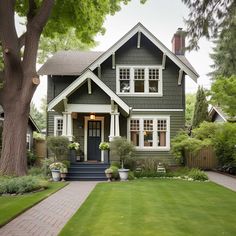 a gray house with white trim on the front door and windows is surrounded by greenery