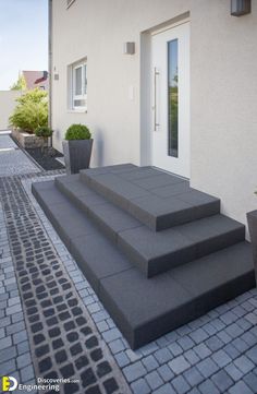 the steps are made of concrete and have planters on each side, along with potted plants