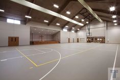 an empty indoor basketball court with lights on