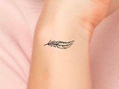 a woman's arm with a small feather tattoo on the left side of her wrist