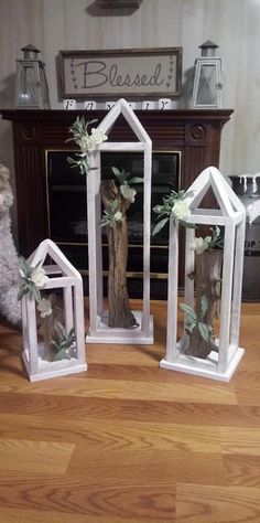 three white wooden houses with flowers and greenery in them sitting on a hard wood floor