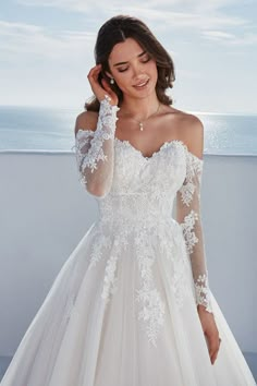 a woman in a wedding dress posing for the camera with her hand on her head