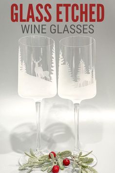 two wine glasses sitting next to each other on top of a white table with holly and red berries