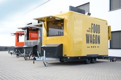 three food trucks parked in front of a building with the doors open and windows closed