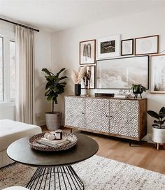 a living room filled with furniture and pictures on the wall next to a large window